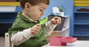 Toddler holding items to put in a pink box